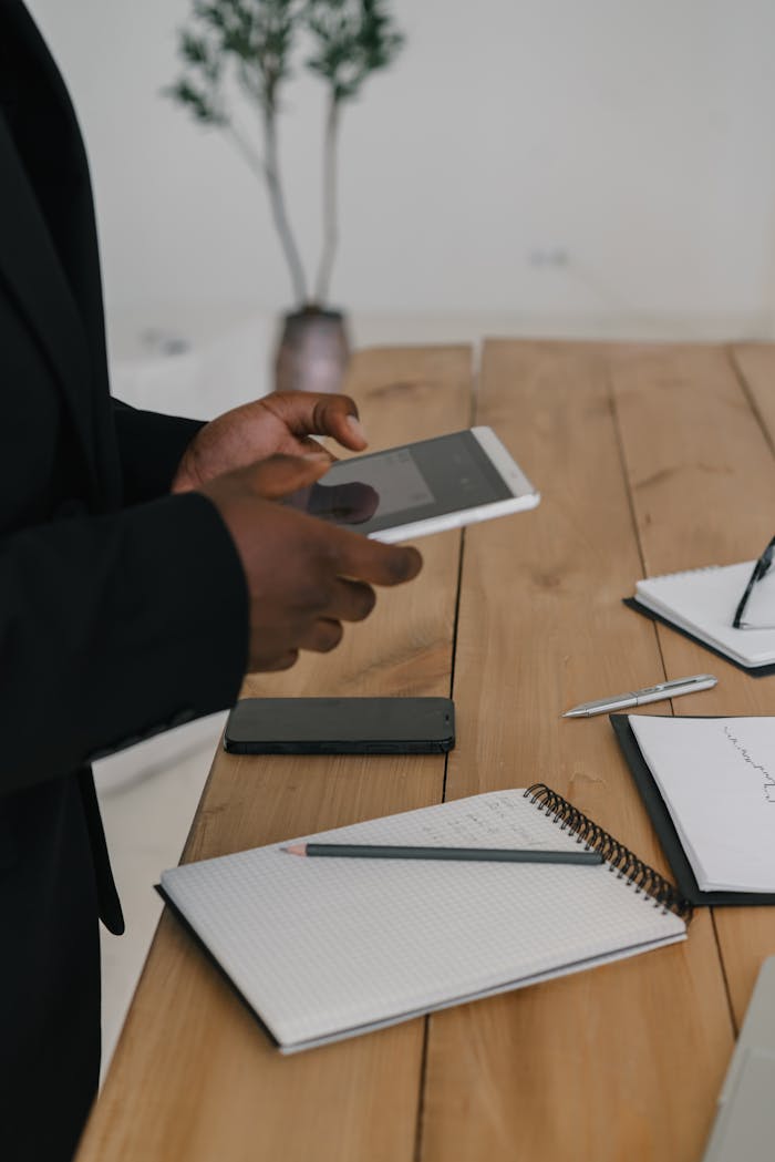 services-01 A business professional using a tablet at a wooden desk with stationery items.